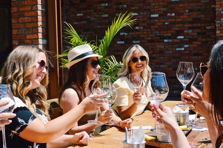 A group of women drinking wine in the sun.